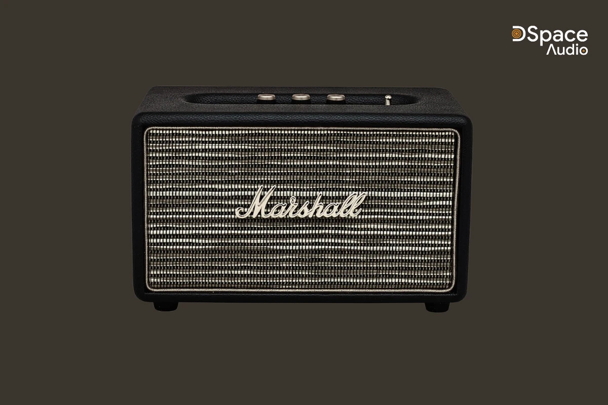 Marshall Acton sở hữu kiểu dáng hình hộp vuông vức, nhỏ gọn với kích thước 260 x 160 x 150 mm và trọng lượng chỉ 2,85kg. Vỏ ngoài được bọc da vinyl cao cấp, các góc bo tròn mềm mại, mặt trước là lưới kim loại chắc chắn in logo Marshall nổi bật – tất cả tạo nên một tổng thể vừa cổ điển, vừa sang trọng, đậm chất rock.